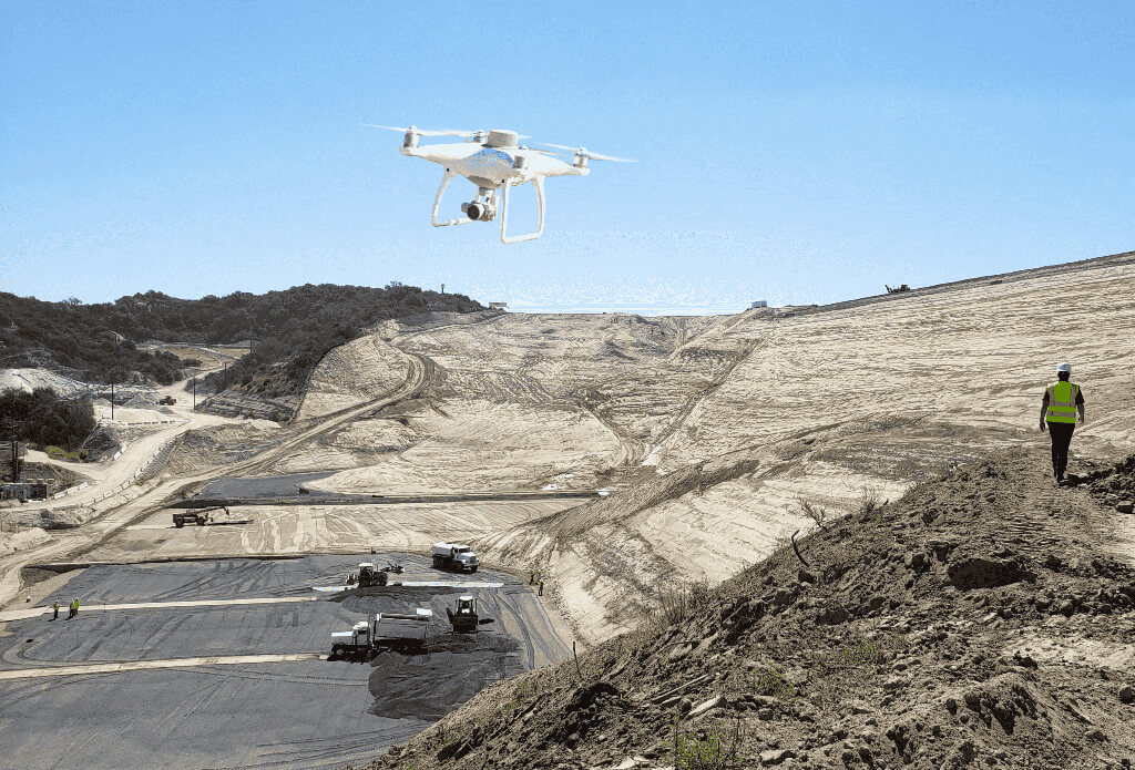 Phantom 4 RTK flying over a waste management site with the site manager walking in the foreground.