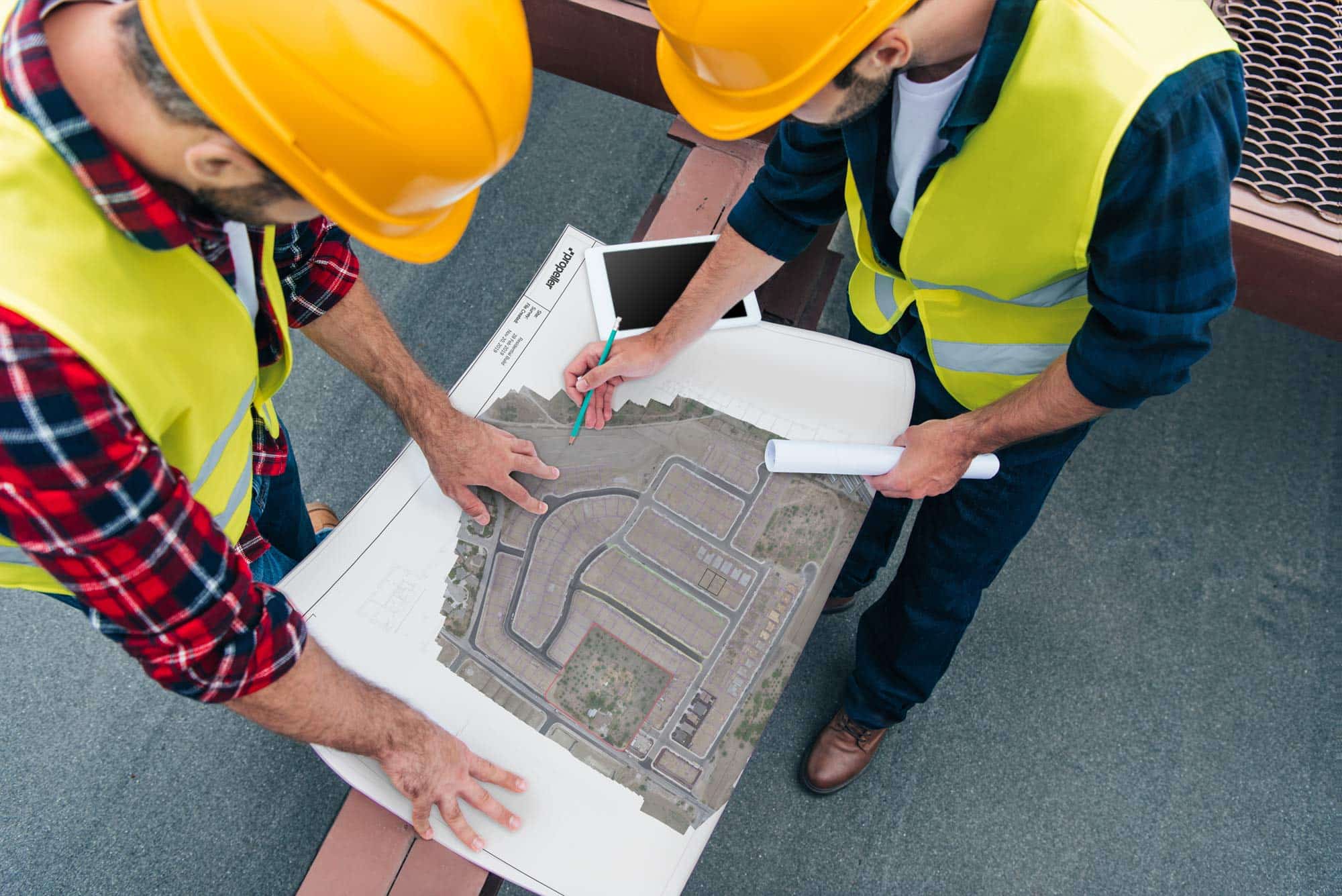 Overhead photo of two site workers looking at a development map.