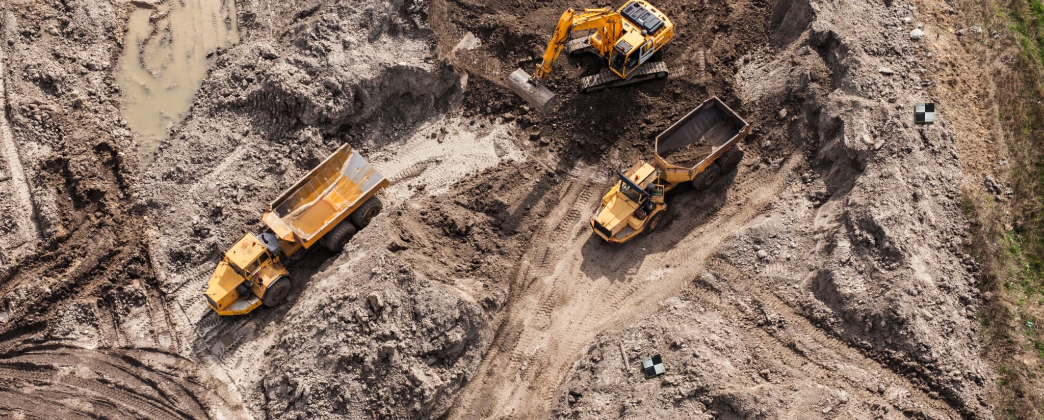 Overhead photo of a construction site showing two trucks and a digger.